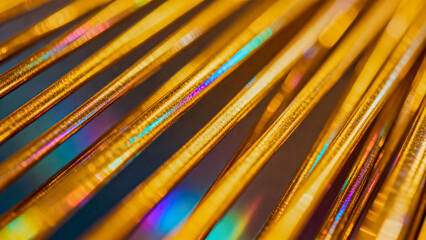Diagonal gold metallic lines and sticks form a vibrant abstract background, with iridescent colors and changing scale creating depth and motion.