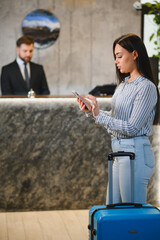 Woman guest checking in hotel lobby using smartphone