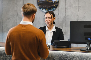 Guest discussing check in with hotel receptionist at front desk