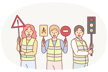 Traffic controllers urge young children to be careful while driving, holding road signs in hands