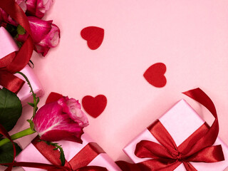 Beautiful and festive background for valentines day or anniversary celebration in pink with pink present and red ribbons roses and copy space