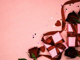 Beautiful and festive background for valentines day or anniversary celebration in pink with pink present and red ribbons roses and copy space