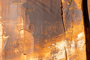 Ancient petroglyphs etched into the dark desert varnish of Wall Street's red sandstone cliffs in Moab, Utah, depict bighorn sheep, hunters with bows, and mysterious geometric patterns from the Fremont