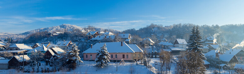 A picturesque panorama generic winter village scene. A tranquil and beautiful rural mountain scene with snow-covered rooftops and a peaceful atmosphere