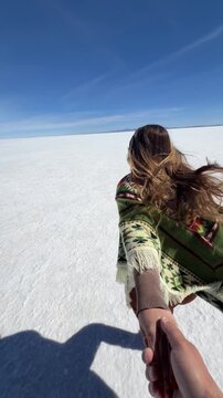 Couple running together on Salar de Uyuni salt flat, Bolivia