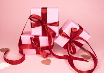 Beautiful and festive background for valentines day or anniversary celebration in pink with pink present and red ribbons roses and copy space