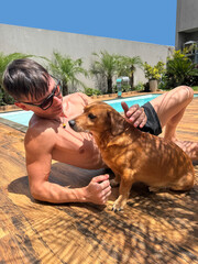 homem com cachorro em area de lazer com piscina 