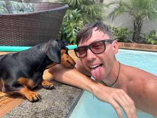 homem com cachorro em area de lazer com piscina 