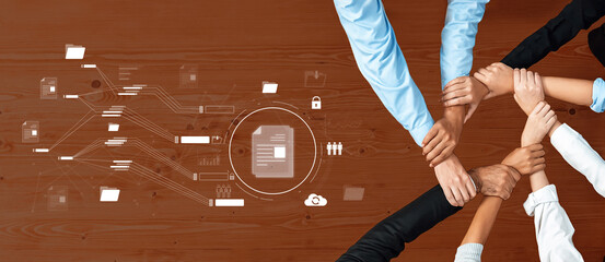 Diverse hands come together on a wooden table symbolizing collaboration in a professional workspace, enhanced by digital graphics representing data security and teamwork. Trope