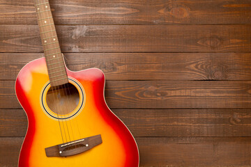 Bright acoustic guitar on wooden background, top view
