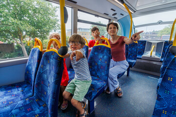 Naklejka premium Family of four enjoying a fun bus ride while pointing outside