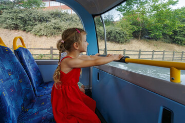 Young girl passenger enjoying bus ride while looking outside