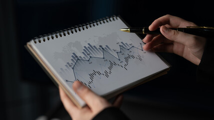 A person holding a notepad with financial graphs, symbolizing market analysis and investment...