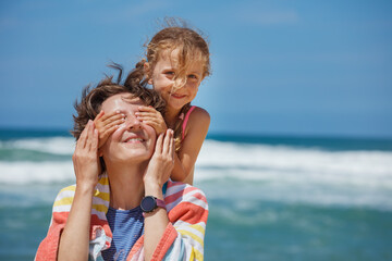 Daughter surprise mom closing her eyes came from behind on beach