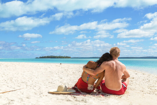 Tourist couple sitting on the beach, One Foot Island, Aitutaki, Cook Islands