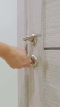 Key rotation releases door latch smoothly, Careful turning of key unlocks passage with silver handle, Gently rotating key to unlock door reveals corridor and latch details with clarity