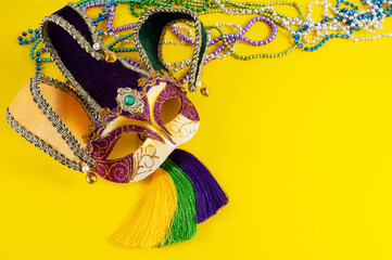 Top view of a beautiful composition of colorful masks, confetti, Mardi Gras decorations. Yellow Mardi Gras banner.