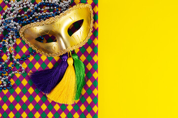 Top view of a beautiful composition of colorful masks, confetti, Mardi Gras decorations. Yellow Mardi Gras banner.