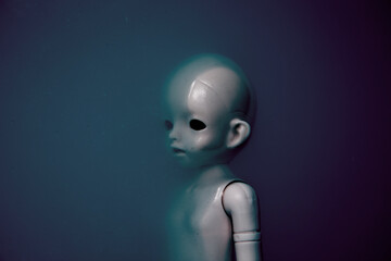 Creepy doll face in dark dirty blue water