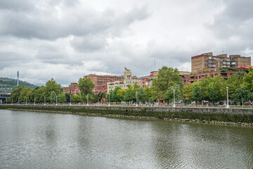 Obraz premium A view from the embankment of the Nervion River in Bilbao, Spain, showing a part of the city The weather is cloudy the sky is covered with clouds.