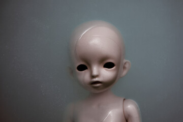 Creepy doll face in dark dirty water