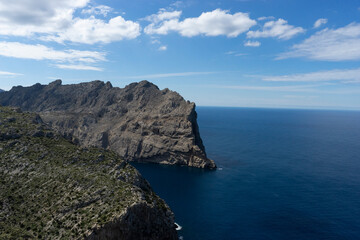 Rocky cliffs overlooking the blue ocean under clouds.. Palma de Mallorca, Spain