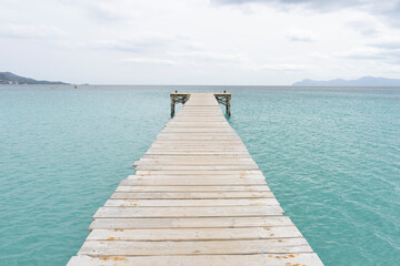 Obraz premium Wooden pier extending into calm turquoise water.. Palma de Mallorca, Spain