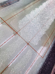 Macro shot of frozen morning dew and ice crystals on a glass window panel on a cold winter day showing the beauty of nature and freezing temperatures in the local countryside area