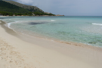 Sandy beach with clear turquoise water and mountains.. Palma de Mallorca, Spain