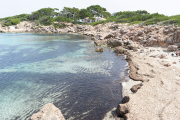 Rocky coastline with clear water and greenery.. Palma de Mallorca, Spain