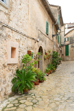 Narrow street with stone buildings and potted plants.. Palma de Mallorca, Spain