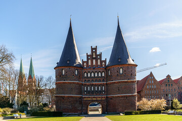 Establishment of the Holstentor Museum in Lubeck, Germany Three sharp church towers and various buildings are visible along the edges. Green grass is ahead The weather is sunny