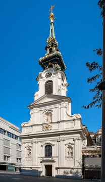 Vor einem wolkenlosen Himmel erhebt sich die denkmalgesch&uuml;tzte Stiftskirche "Zum Heiligen Kreuz" in Wien, Ansicht von S&uuml;dosten - Inschriften retuschiert