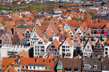 A city Lubeck in Germany with many red and white houses. The houses are all different sizes and shapes. The houses are all lined up in a row