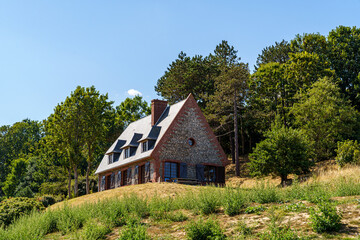An old red brick house stands on a hill in France, in Normandy The house stands on a hill surrounded by green forest