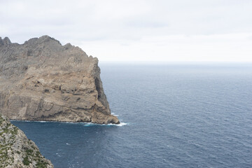 Fototapeta premium Rocky coastline meets the calm sea under cloudy sky.. Palma de Mallorca, Spain