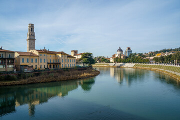 A Adige river in Verona Italy runs through a city with a large building in the background The water is calm and the sky is clear