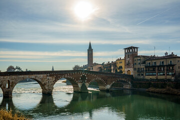 The Ponte Pietra bridge over the Adige River in Verona, Italy, and part of the city. Photographed against the sun. The shot is very expressive