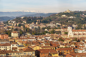 A panorama photographed from above the city of Verona in Italy The sky is blue and the Alpine panorama is visible in the background The mountains are covered in snow