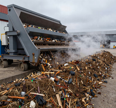 Industrial composting facility: a large windrow turner moves through steaming organic waste