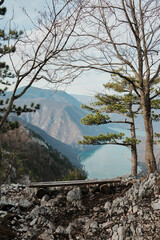 Wooden bench on rocky edge with view of Drina River and Perucac Lake framed by trees in Tara National Park, Serbia. Calm mountain landscape and deep canyon.