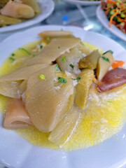 A healthy dish of artichokes cooked with olive oil and vegetables served in a delicious sauce on a white plate in a professional restaurant kitchen for people who enjoy vegan meals now
