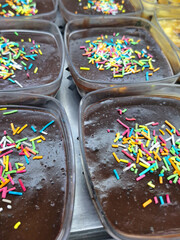 Several containers of smooth chocolate pudding or mousse topped with colorful sprinkles served in a restaurant display as a tasty and sweet dessert for kids and adults alike