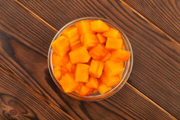 chopped persimmon on brown wood background top view