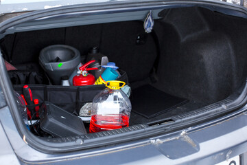 Car trunk filled with various tools and supplies including fire extinguisher, cleaning products, and a funnel, showcasing organized storage for automotive maintenance tasks © Krystsina