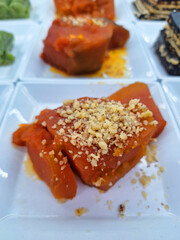 A delicious plate of traditional Turkish pumpkin dessert topped with crushed walnuts served on a white plate in a restaurant setting with a focus on the bright orange texture of food