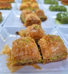 A high quality close up of authentic Turkish baklava with layers of thin dough and ground pistachios served in a white plate with bright lighting highlighting the crispy sweet texture