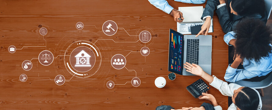 A diverse group of professionals engages in a business meeting, analyzing financial data while discussing legal concepts, surrounded by digital icons on a modern desk. Trope - Powered by Adobe