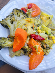 A close up of a healthy vegetable salad plate featuring steamed broccoli and orange carrots with some red peppers served in a bright restaurant setting for a nutritious vegan meal