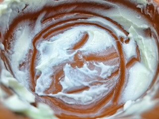 Macro shot of the inside of a rustic clay bowl containing the remains of a thick white dairy product like yogurt or cream showing circular textures and a traditional pottery style